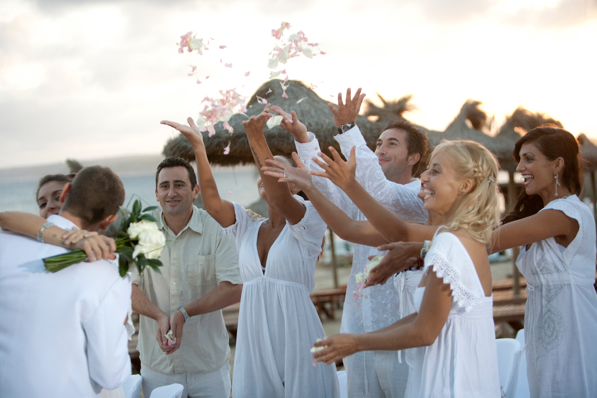 Invitados lanzando pétalos al aire al atardecer