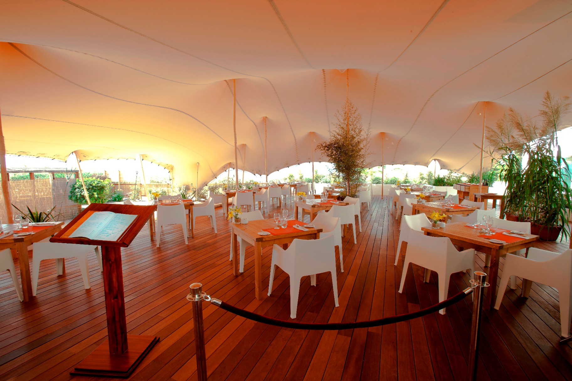 Interior del restaurante bajo carpa con mesas de madera