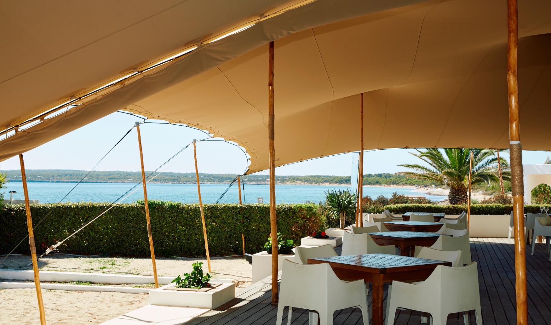 Terraza del restaurante bajo carpa con mesas y vista al mar