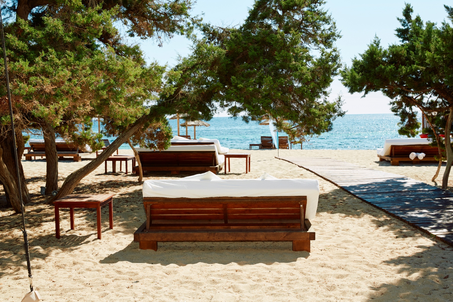 Daybeds sobre la arena junto a la pasarela con vistas al mar